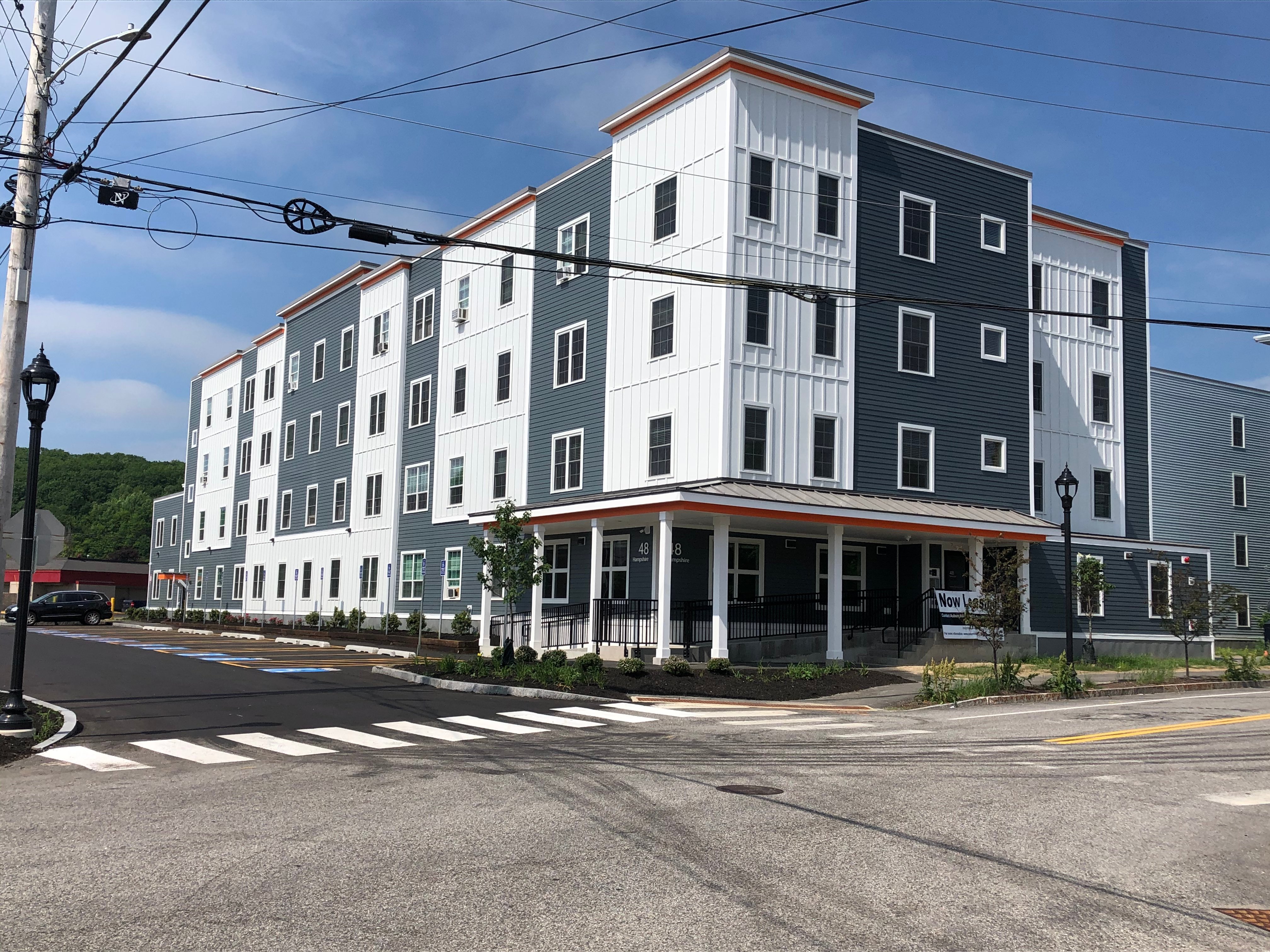 A street view of a multi-story building with a crosswalk in front.